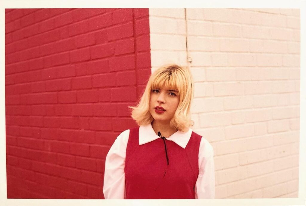 Photo of a person wearing a vintage outfit with a maroon knit vest