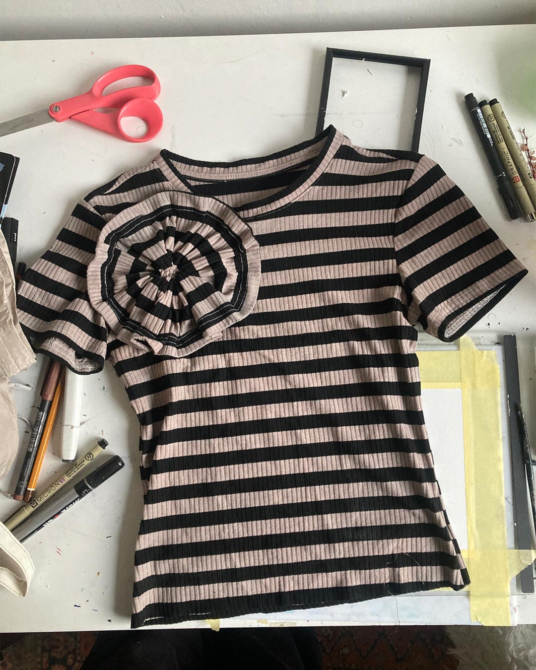 Flat-lay photo of a reworked vintage baby tee with cockade